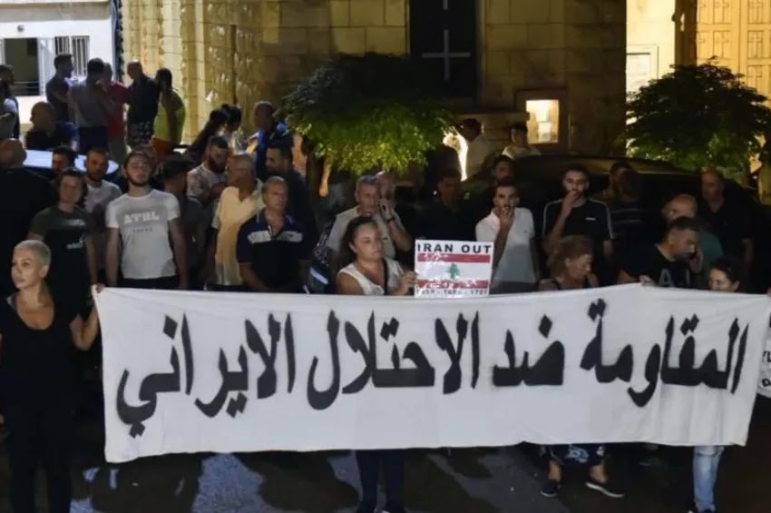 Manifestantes carregam uma faixa com os dizeres 'Resistir contra a ocupação iraniana' em árabe na cidade cristã de Kahaleh, Líbano, em 9 de agosto de 2023. Um caminhão carregando armas para o militante Hezbollah caiu em Kahaleh. Duas pessoas foram mortas em confrontos entre membros do Hezbollah e moradores da cidade cristã | Foto de Wael Hamzeh/EPO-EFE