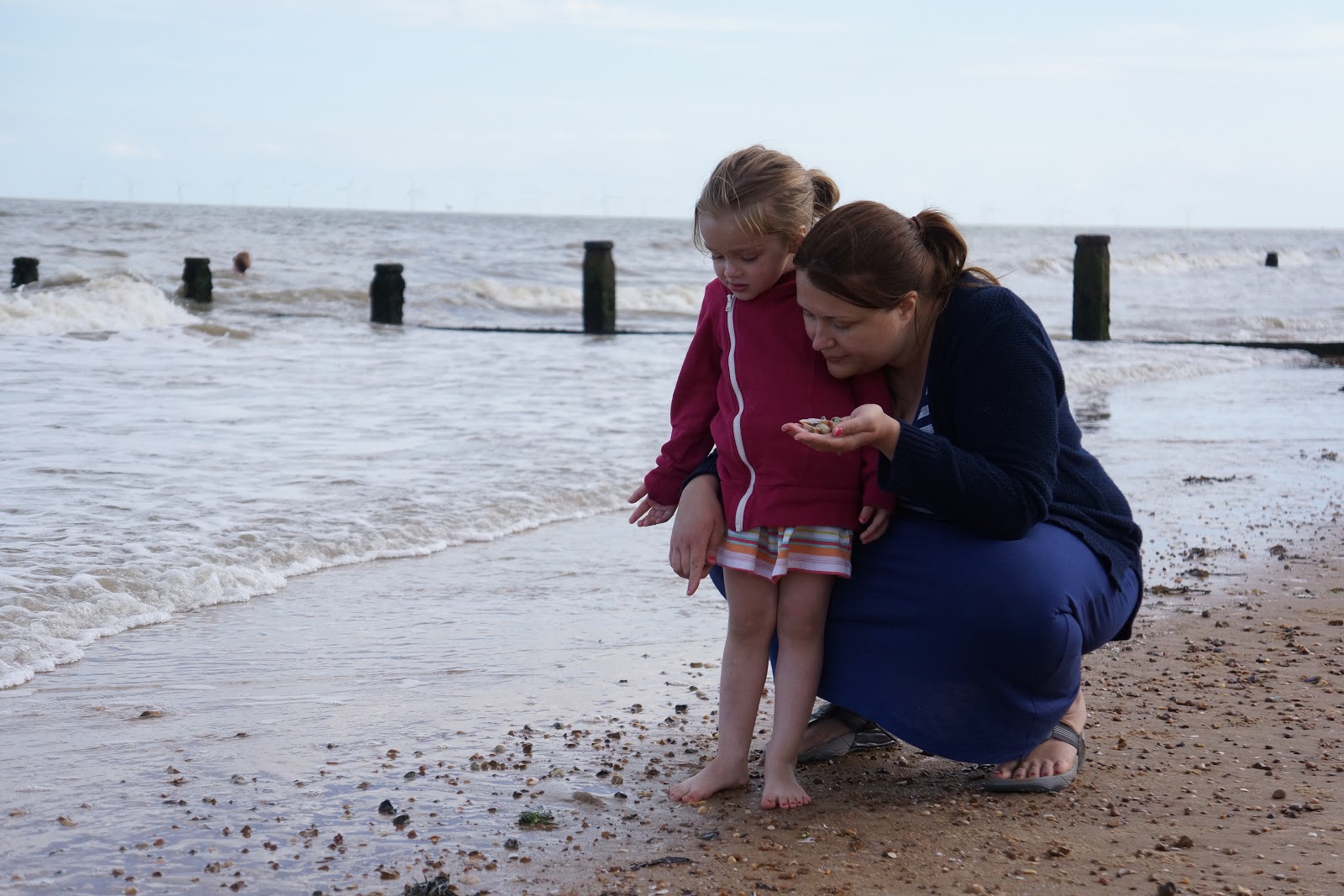 mum collecting seashells with daughter