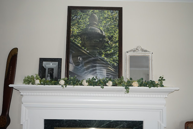 Mantel decorated with rose garland, chippy paint mirror, large urn picture