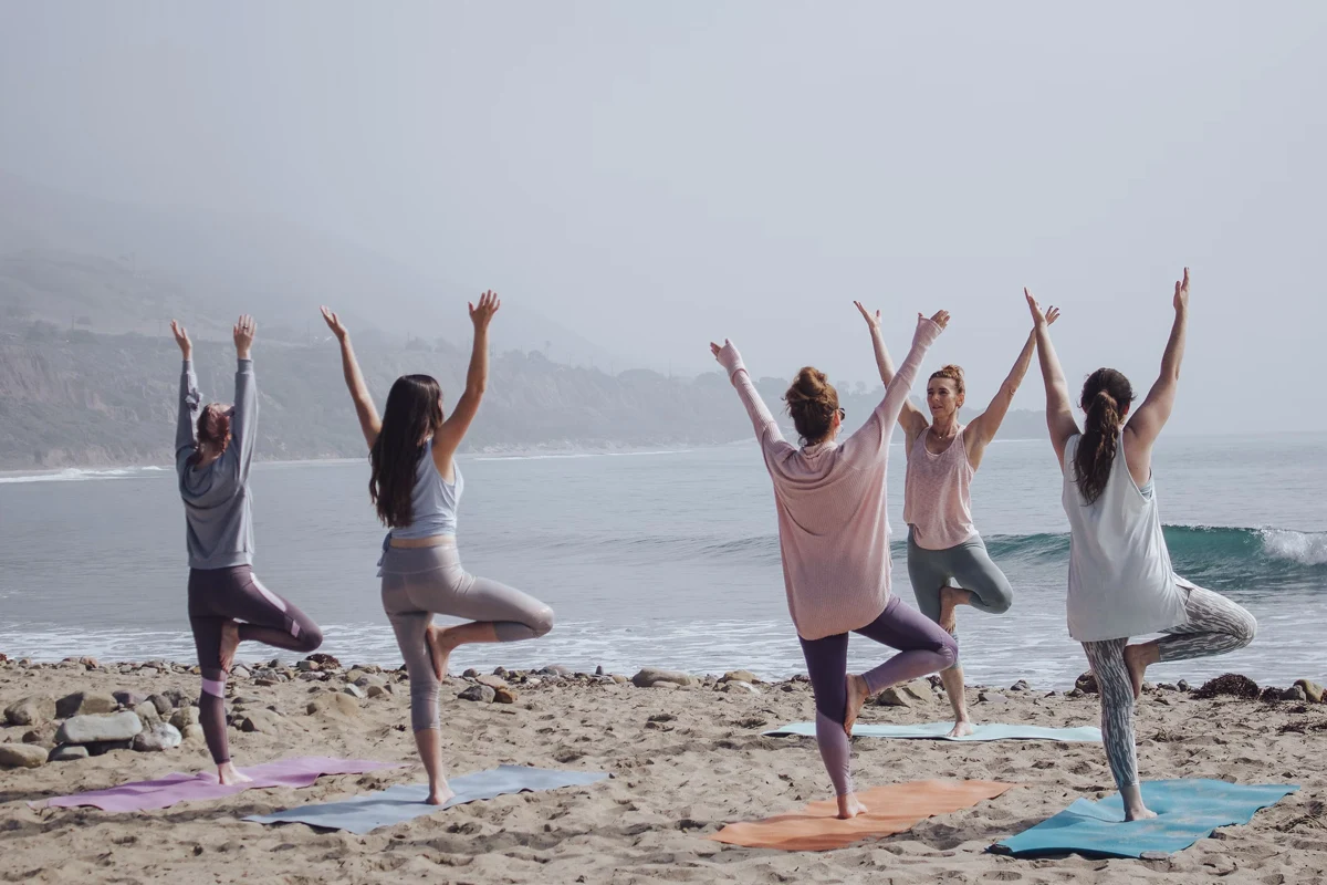 a group of women doing yoga on a beach