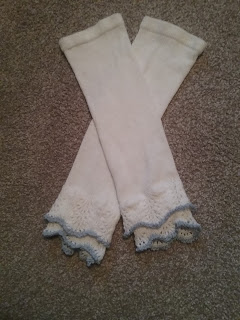 Two white knitted tubes with hung hems at the top edges, terminating in two layers of lacey scalloped frills, each edged with a narrow blue border.