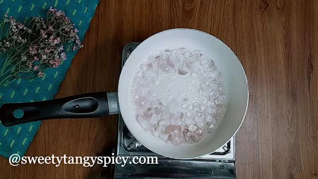 Onions and garlic sizzling in a pot with olive oil, creating a flavorful base for tomato basil soup.