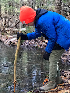 Boy in orange hat pokes ice with a stick