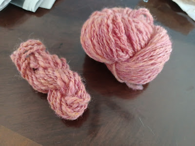 one mini-skein of lumpy yarn and one medium-small skein of nicer yarn, both pomegranate pink