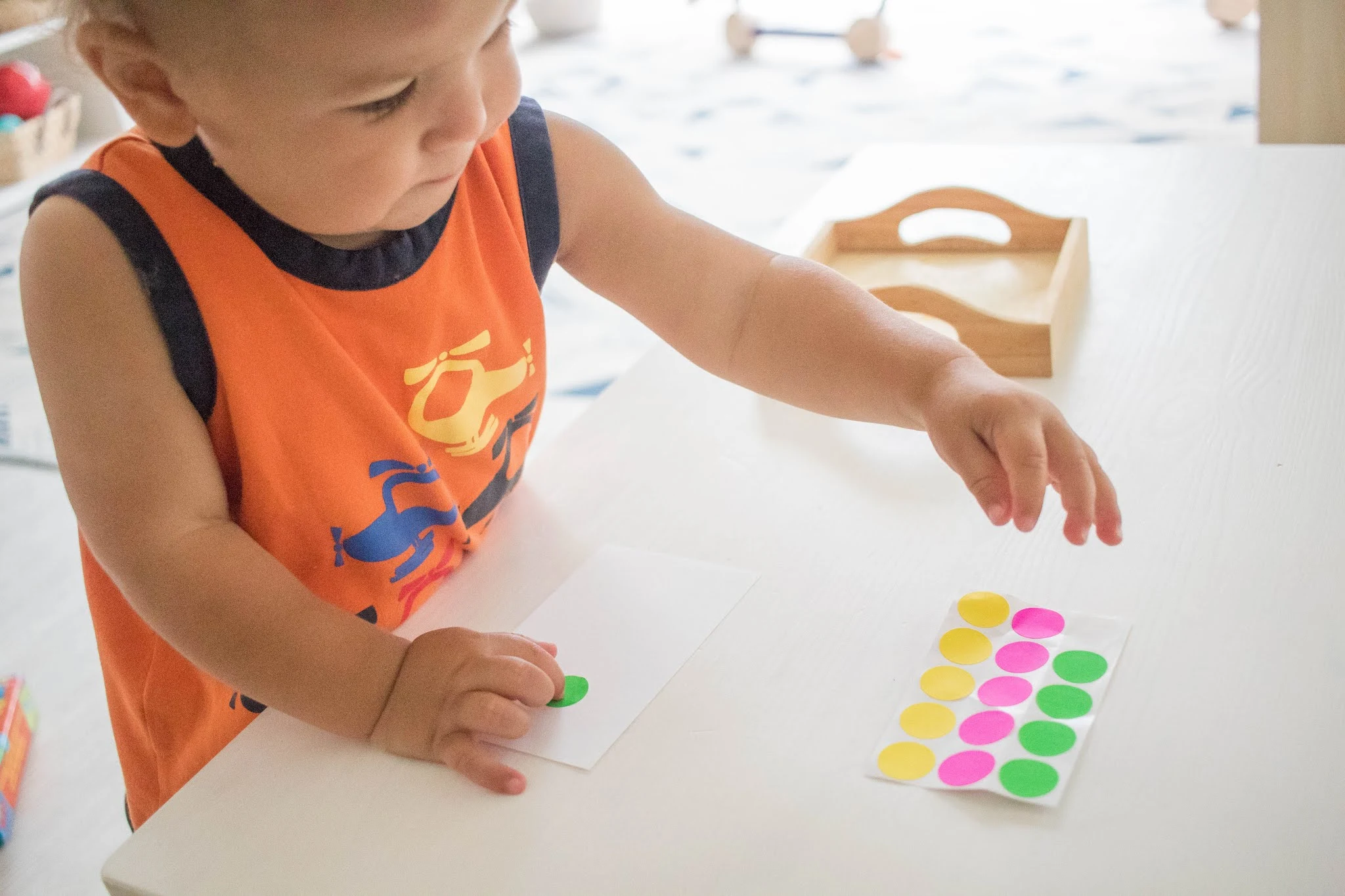 Young Montessori toddler places stickers on a paper while working with art material