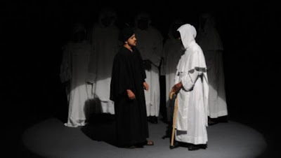 Grupo “Teatro Biblio”. Obra de teatro: Sermón de Adviento, 17 de mayo del 2011.  Sala Ravelo del Teatro Nacional, Plaza de la Cultura “Juan Pablo Duarte” en la Avenida Máximo Gómez, Santo Domingo, Distrito Nacional. Actores de pié. Frailes vestidos con túnica o hábito blanco, escapulario con capuchón cubriendo la cabeza, correa o cíngulo, cogulla o túnica amplia con grandes mangas. Comendador vestido con amplio ropaje largo de color negro con amplias mangas largas con un sombrerito. En primer plano, de izquierda a derecha, en actitud de diálogo: Hugo Albuerme (comendador), Alexis Román (fraile). Detrás, en la penumbra, uno al lado del otro, los frailes: María Esther Abreu, Arlene Severino, Martín Saldívar, Maira Fernández, Amarilis Méndez.