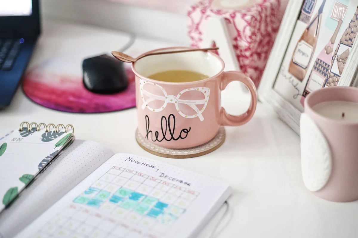 aesthetic work table set-up with a cup of coffe, an opened planner and a laptop