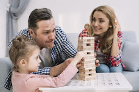 Una niña juega a la Jenga con su padre y su madre.