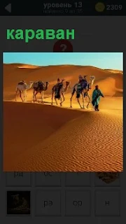 В пустыне идет караван верблюдов с погонщиками и поклажей на спинах, преодолевая песчаные холмы
