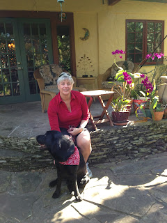 Michele is sitting on the patio and holding Rory who is looking back over his right shoulder.   Karen his breeder host was probably off doing obedience with Lightning.