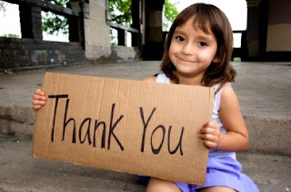 Little girl holding cardboard thank you sign.