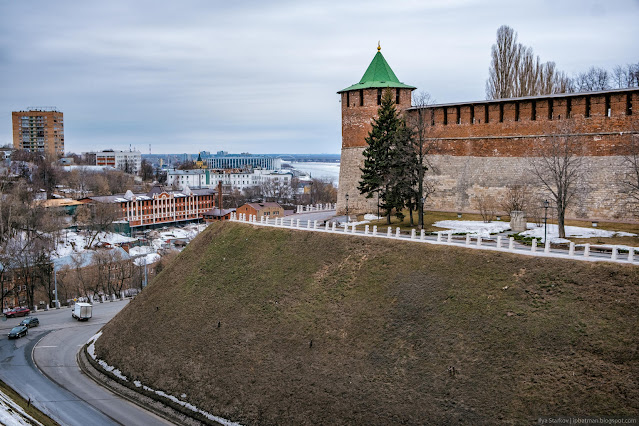 Дорога с машинами вдоль крутого склона холма и башня кремля наверху