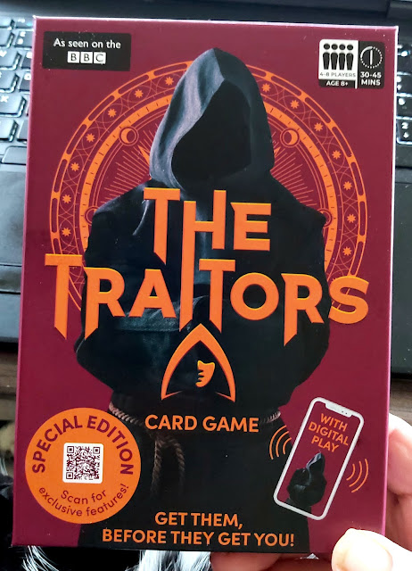 Pack front The Traitors strategy card game showing Egyptian style mysterious decor and mystery human wearing black hooded robe