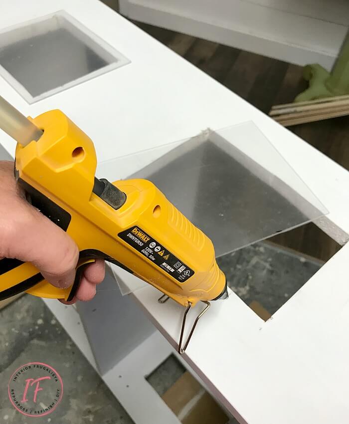 Turn an IKEA Billy Bookcase into a charming dollhouse with plexiglass windows, adorable window boxes, and a repurposed jewelry box chest front door.