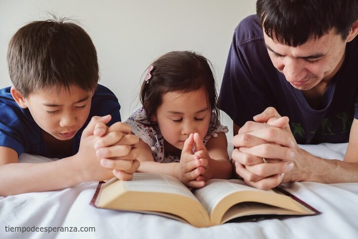 Padre orando con sus hijos antes de leer la Biblia