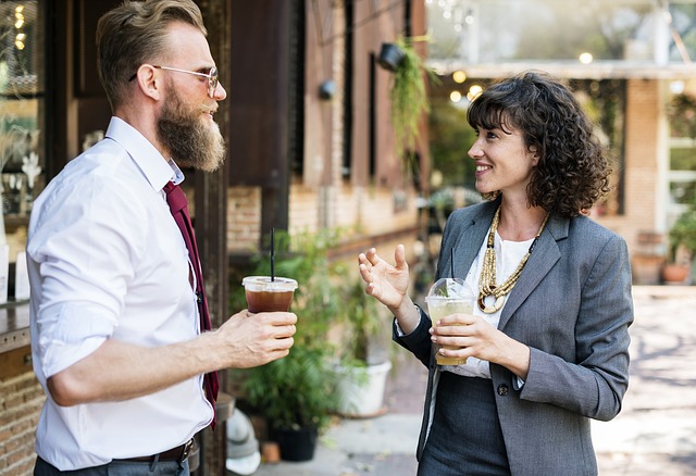 コーヒーを飲みながら会話する女性とヒゲの男性