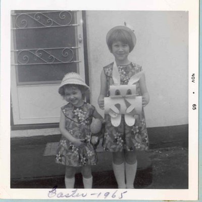 Two sisters in new Easter dresses standing by the front door.