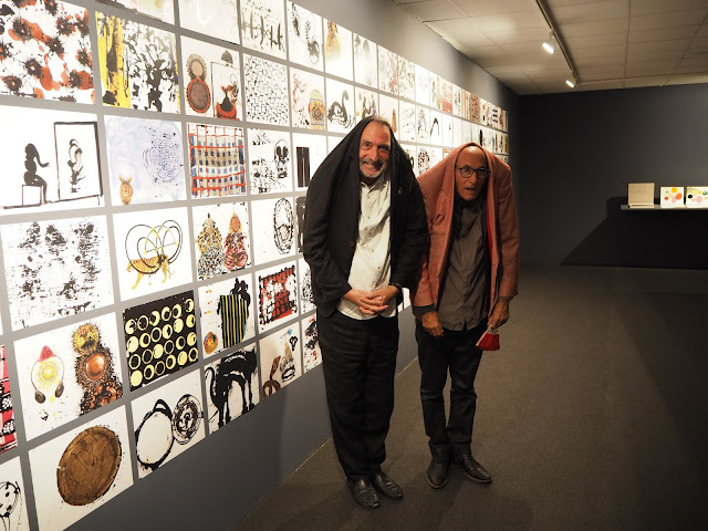 Frederic Amat i Vicenç Altaió posen junts en una divertida imatge davant algunes de les obres que recull l'exposició "Espai Llibres".