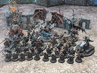 A Slaves to Darkness army lined up on a gaming table. They are painted in a black, red and gold scheme with a red kraken motif on their shields