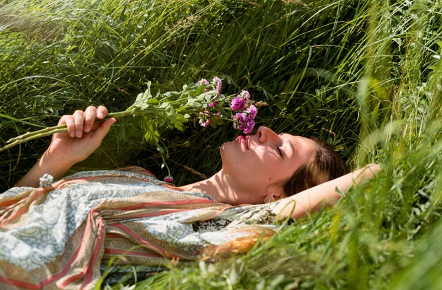 Woman smelling flowers lying in the field relaxed