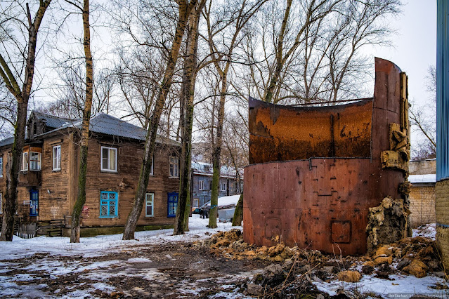 Старый деревянный дом и разрезанный металлический бак