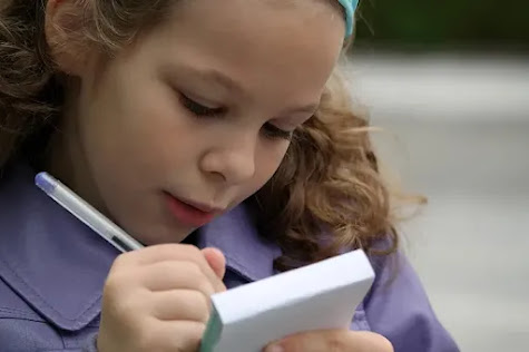 Little girl writing in a book