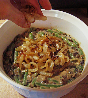 Hand Spreading Onions Over Top of Casserole