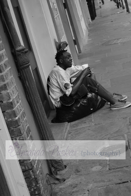 Black and white of New Orleans man sitting on street with trash