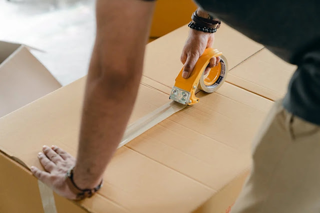 A man packing a box with scotch tape