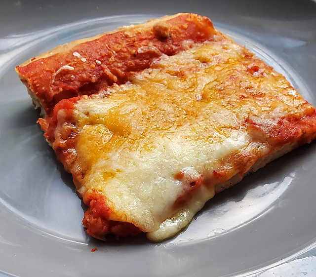 a large slice of school cafeteria pizza