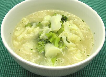 Niet gepureerde bloemkool broccolisoep met melk en gebonden met bloem, geserveerd met geraspte cheddar kaas