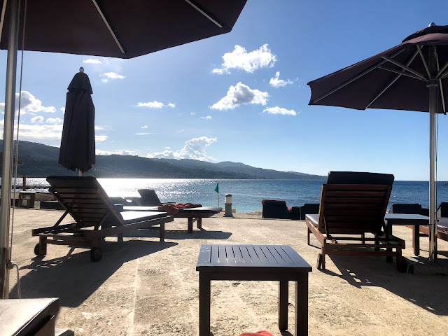 A sunny day looking from the pool deck to Montego Bay. Umbrellas and loungers are visible.