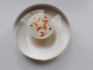 Domed resin paperweight containing a MS Society badge