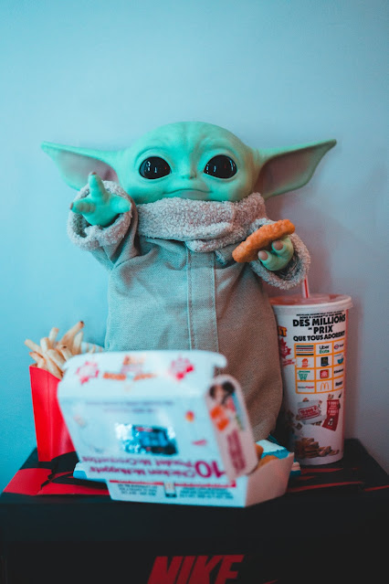 Grogu toy holding and surrounded by McDonald's food