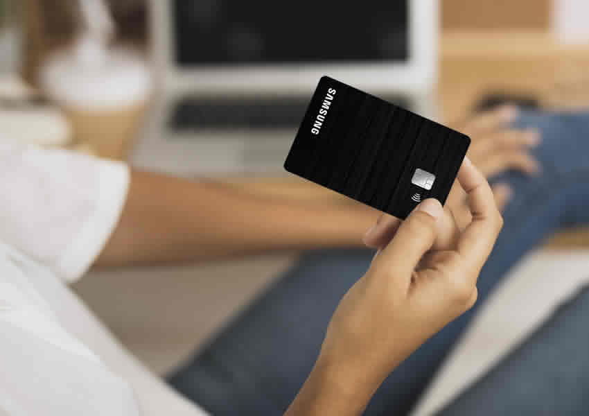 Imagem mostra uma pessoa segurando o cartão de crédito Samsung Itaucard com uma das mãos.