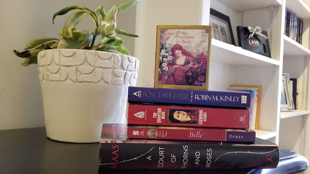 stack of Beauty and the Beast inspired books next to a plant in a white pot