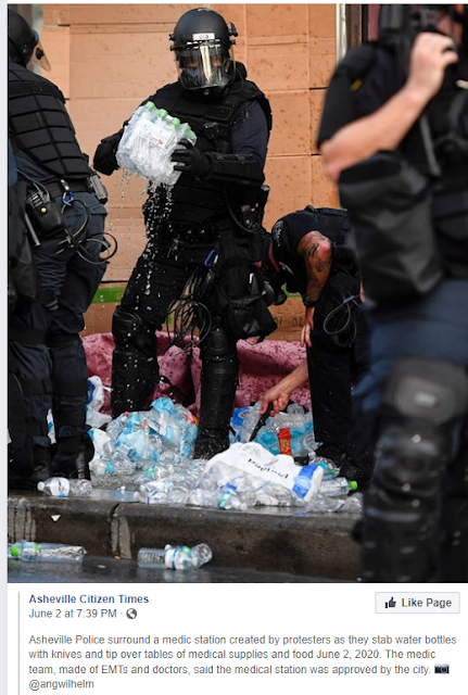 Asheville Police surround a medic station created by protesters as they stab water bottles with knives and tip over tables of medical supplies and food June 2, 2020. The medic team, made of EMTs and doctors, said the medical station was approved by the city. 