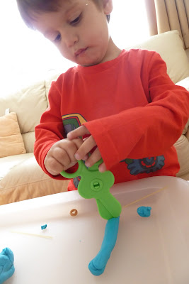 Child cutting play dough with plastic scissors