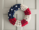 A wreath made from red, white and blue flowers with white stars attached top left.