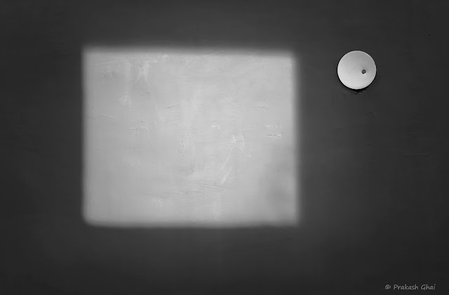 A Black and White Minimal Art Photograph of a Square formed by Light versus a Small White Circle