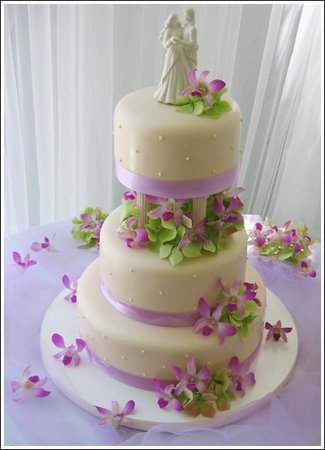  cake decorated with purple orchids green leaves and lavender satin 