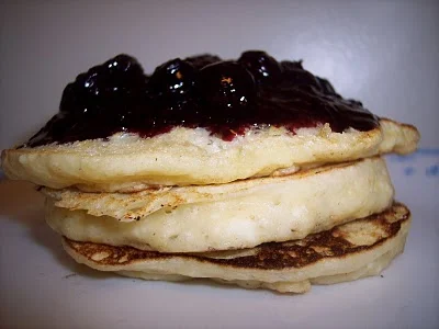 Stack of lemon ricotta pancakes with berry sauce.