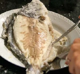 Limpiando la dorada, recién sacada del horno, de piel y espinas