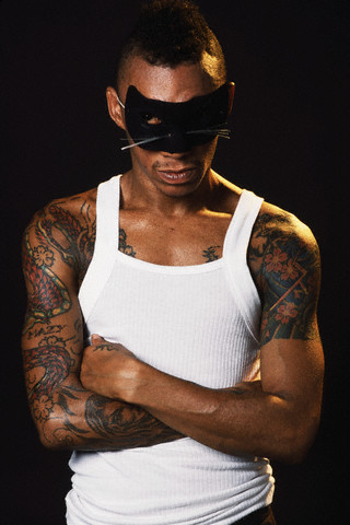 Black man with a mask having sleeve dragon tattoo to chest
