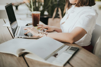 woman in white shirt sitting on chair and working on laptop