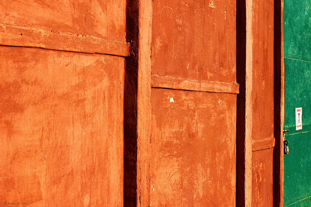 Minimalist Photo of Lines on an Orange Textured Indian wall with a Green Door.