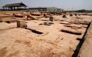 The image shows a field of dirt and bricks with a building visible in the background. The building is wooden with a white roof. The dirt is brown and has a lot of texture. The building is wooden with a white roof. The building is wooden and has a lot of texture.