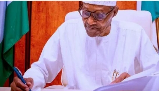 Alt: = "President Muhammadu Buhari signing document"