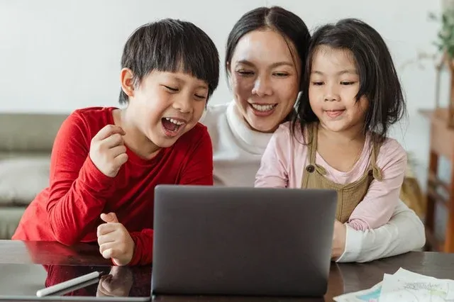 A mother and her children in front of a laptop