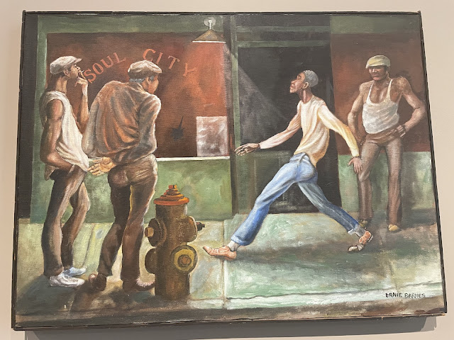This painting was done by a black artist depicting the life of a black man in a downtown area. He is seen walking with his head held high, nicely dressed, with a smile on his face while three white men dressed sloppily in wife beaters and tattered clothes look on with scowls.